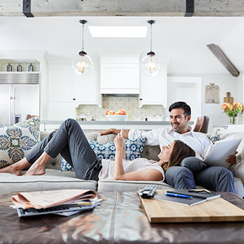 Young Couple relaxing on sofa in living room looking at mobile phone together after work